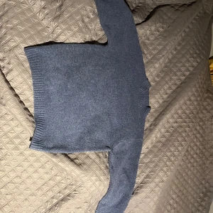 Blå stickad tröja från Uniqlo - Säljer en stilren blå stickad tröja från Uniqlo i storlek XS. Tröjan har en klassisk design med ribbade muddar vid ärmslut och nederkant, perfekt för kyligare dagar. Använd cirka 3 gånger. Nypris 500kr och mitt pris 250kr.