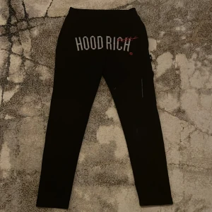  Hoodrich byxor - Snygga svarta byxor från Hoodrich med tryck i vitt och rött. Byxorna har en tight passform och är perfekta för en avslappnad stil. De har elastisk midja och textdetaljer längs benet. Använd max 2-3 gånger, köptes för 1200 och är slutsålda i alla butiker, säljer pga dom är för små