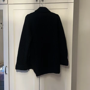 Svart och vit stickade polotröjor - Mysig svart och vit stickad polotröja med långa ärmar och ribbade detaljer. Perfekt för kyliga dagar när du vill hålla dig varm och stilren. 