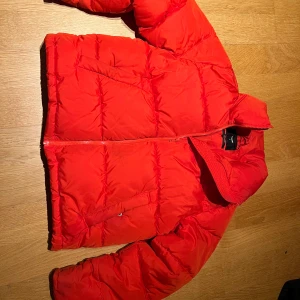 Röd pufferjacka från Bik Bok - Säljer en snygg röd pufferjacka från Bik Bok. Jackan har en dragkedja framtill och är perfekt för kyligare dagar. Den är i storlek M och har en modern look.