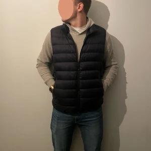 Mörkblå dunväst - Snygg mörkblå dunväst med dragkedja, perfekt för lager-på-lager under kyliga dagar. Västen har en stilren design och passar bra över en tröja eller hoodie.