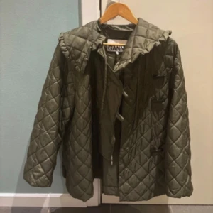 Olivgrön quiltad jacka från Ganni - Snygg olivgrön quiltad jacka från Ganni med huva och knäppning framtill. Perfekt för kyligare dagar med sin stilrena design och praktiska detaljer🌟storlek xxs men sitter mer som en s/xs, en knapp saknas