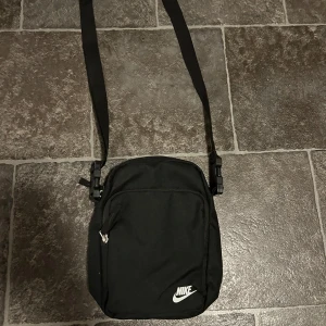 Svart axelväska från Nike - Hej, jag säljer min lilla Nike väska. Jag köpte den för jag trodde jag skulle använda den men har aldrig använt den. Så den är i princip ny