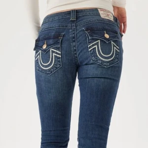 Blå bootcut jeans med broderade fickor - Snygga blå bootcut jeans med unika broderade detaljer på bakfickorna. Knappt använda  intressekoll