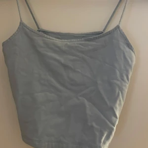 Ljusblå linne  - Gullig ljusblått  linne med tunna axelband. Perfekt för varma dagar eller som lager under en tröja. Ganska kort.