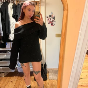 Svart offshoulder tröja - Snygg svart offshoulder tröja med långa ärmar. Perfekt för en stilren look. Tröjan har en ribbad struktur som ger en extra touch av elegans. Passar som klänning med minishorts under