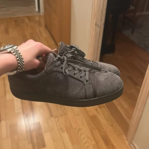 Grå loubitin utan nitar - Snygga grå sneakers från Louboutin i mocka med klassisk röd sula. Skorna har snörning och en stilren design som passar perfekt för en trendig look.