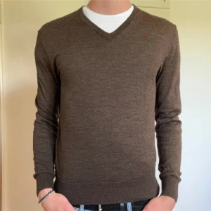 Brun tröja från Polo Ralph Lauren - Säljer en stilren brun tröja från Polo Ralph Lauren i merinoull. Tröjan har en v-ringad design och långärmade ärmar. Perfekt för en elegant och bekväm look. Pris kan diskuteras.