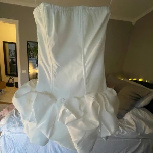 Vit axelbandslös klänning från PrettyLittleThing - Snygg vit axelbandslös klänning från PrettyLittleThing med volangdetaljer. Perfekt för studenten! Klänningen har en figurnära passform. Jag säljer då den var lite för stor på mig. Helt oanvänd med prislapp kvar💕💕