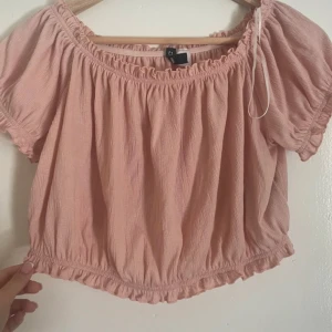 Rosa offshoulder topp från H&M - Söt rosa offshoulder topp från H&M med elastiska kanter och volangdetaljer. Perfekt för varma sommardagar. 💖