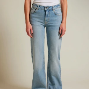 Midwide Jeans 550 27-32 - Snygga blå jeans med hög midja och en klassisk bootcut-stil från Bik Bok. Perfekta för en avslappnad look med en vit t-shirt eller en stickad tröja. De har en tidlös design med fem fickor och knappgylf. Haft den på mig bara 2-3 gånger.