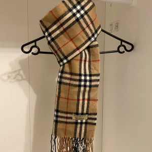 Burberry - Säljer nu denna snygga burberry halsduk i mycket fint skick utan defekter. Den är gjord i 100% lammull och passar perfekt nu i vinter. Hör av er vid funderingar. 