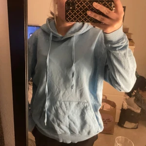 Ljusblå hoodie - Säljer en ljusblå hoodie med luva och dragsnören🩵 Tröjan har en stor ficka framtill och långa ärmar med ribbade muddar. Den är från misslisibells kollektion med NA-KD🤗 Oversized