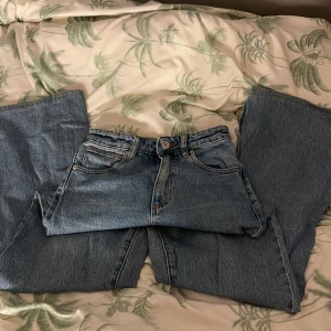 Blå jeans med hög midja - Säljer ett par klassiska blå jeans med hög midja. De har en rak passform och traditionella femficksdetaljer. Perfekta för en avslappnad stil.