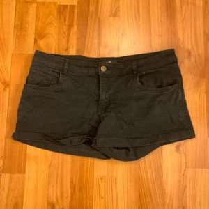 Svarta shorts från H&M - Snygga Lågmidjade svarta shorts från H&M med knapp och dragkedja framtill. De har två fickor fram och två bak, vilket ger en klassisk look. Perfekta för en avslappnad stil. Storlek 40.