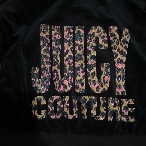 Svart hoodie från Juicy Couture - Snygg svart hoodie från Juicy Couture med leopardmönstrad text på ryggen.