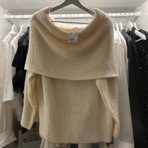 Vit stickad tröja från H&M - Säljer en mysig vit stickad tröja från H&M i storlek M med en bred krage som kan bäras offshoulder. Perfekt för kyliga dagar! Tröjan är helt oanvänd och lappen sitter kvar! Har du några frågor eller funderingar så ska du inte tveka på att höra av dig⭐️