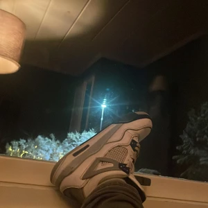 Nike Air Jordans i vitt och grått - Säljer ett par klassiska Nike Air Jordans i vitt med grå och svarta detaljer. Skorna har snörning och den ikoniska Jumpman-loggan på tungan och sulan. Perfekta för sneakerheads som vill ha en tidlös stil.