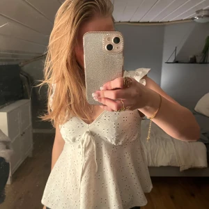Vit ärmlös blus med spetsdetaljer - Säljer en söt vit blus med spetsdetaljer och knytning framtill. Blusen är ärmlös och har en luftig passform.💕