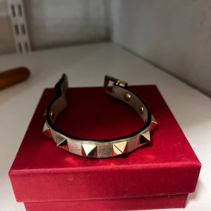 Valentino armband - Valentino armband, guldglittrig färg och beige med guldiga nitar. Skit snyggt men använder tyvärr inte guld. Kommer med box och extra nit. Kan även tänka mig att byta!❣️