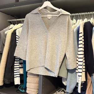 Grå tröja från H&M - Säljer en stilren grå tröja från H&M i storlek XS. Tröjan har en v-ringad design och trekvartsärmar, perfekt för en avslappnad look. Den är tillverkad i ett mjukt material som ger en bekväm passform.