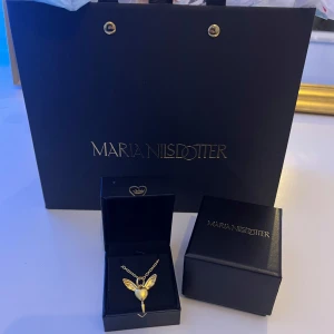 Guldhalsband från Maria Nilsdotter - Säljer mitt ”lovers necklace” från Maria Nilsdotter🩷 Inköpt på NK november 2024 och är i väldigt bra skick, inga defekter. Det är original kedja som är i längd 50 cm💗 Säljer då jag byter till silver så ett byte är ev intressant😊