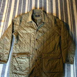 Olivgrön quiltad jacka från Oscar Jacobsson - Säljer en olivgrön quiltad jacka från Brooks Brothers. Jackan har en klassisk krage och knäppning framtill. Den har två stora fickor med lock och en innerficka. Perfekt för kyligare dagar med sin stilrena design. Skicket på tröjan är 6/10 och det finns defekter därför är det ett så billigt pris. Ifall du har fler frågor är det bara att höra av dig!!!
