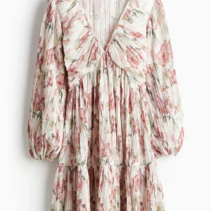 Blommig klänning från H&M - Säljer min blommiga klänning från H&M med långa ärmar och v-ringad design. Klänningen har ett plisserat tyg i rosa och gröna nyanser på en vit bas. Perfekt för vår och sommar! Klänningen är använd få gånger. Originalpriset är 29,99€