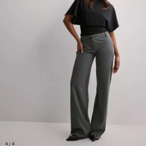 Nelly Low Waist Kostymbyxor  - Snygga grå kostymbyxor med låg midja och en elegant wide fit. Perfekta för en stilren look. Byxorna har en klassisk design som passar till många olika tillfällen.🪩 I toppen skick, skriv för fler bilder eller frågor. (Inte mina bilder!) Nypris: 400kr