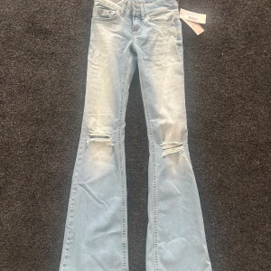 Blå bootcut jeans från Nelly - Snygga blå bootcut jeans från Nelly med låg midja och slitna detaljer på knäna. Jeansen har fickor i bak. De är nyköpta ❤️