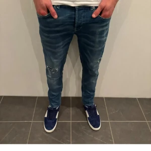Dondup George W33 - Snygga blå jeans med slitningar och en tight passform. De har en klassisk femficksdesign och knappar i midjan. Perfekta för en avslappnad stil.
