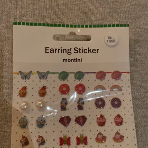 Earring Sticker från Ur&penn  - Ett set med färgglada earring stickers från Montini. Innehåller olika motiv som fjärilar, regnbågar, cupcakes, diamanter och stjärnor. Perfekt för att lägga till en lekfull touch till din stil utan att behöva pierca öronen.