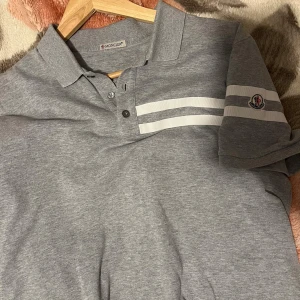 Grå pikétröja från Moncler - Snygg grå pikétröja från Moncler köpt från garmsmarket för 1000kr ny pris 3000kr den är storlek L men sitter som M den saknar industritags men den är äkta 9av10 skick 
