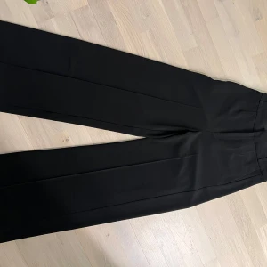Svarta kostymbyxor från InWear - Snygga svarta kostymbyxor från InWear med en elegant wide fit. Perfekta för en stilren look. Tillverkade i en blandning av polyester och viskos för en bekväm passform. Långa ben som även kan läggas ner ytterligare. Passar dig över 170 cm Nypris 1500 kr  