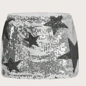 Glittrig silverkjol med stjärnor - Snygg och iögonfallande kortkjol i silver med svarta stjärnor. Kjolen är täckt av paljetter som ger en glittrig effekt. Perfekt för att sticka ut på festen!