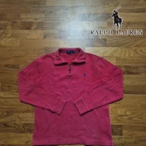 Ralph Lauren half zip röd - Säljer en snygg röd tröja från Ralph Lauren med dragkedja vid halsen. Tröjan har långa ärmar och en liten broderad logga på bröstet. Perfekt för en stilren look.  PRIS KAN DISKUTERAS!! 