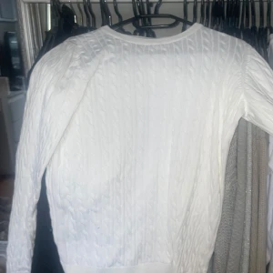Vit flätad tröja  - Säljer en vit flätad tröja från Basic You. Tröjan har ett klassiskt flätmönster och långa ärmar. Perfekt för en stilren och bekväm look. 🌿