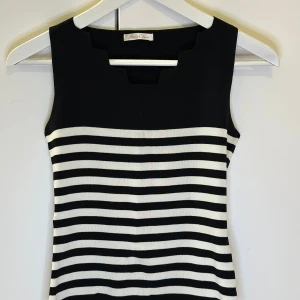 Svart och vit randig ärmlös topp från Marie Claire - Snygg ärmlös topp från Marie Claire i svart och vitt randigt mönster. Den har en unik fyrkantig halsringning som ger en modern touch. Perfekt för en stilren look.