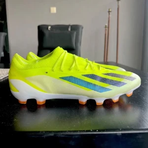 Neongula fotbollsskor från Adidas - Snygga neongula fotbollsskor från Adidas med svarta och blå detaljer. Skorna har en lätt och smidig design med snörning och en slitstark sula för optimalt grepp på planen. Perfekta för den som vill sticka ut på fotbollsplanen. Priset är inte hugget i sten!!