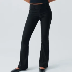 Svarta bootcut byxor - Slutsålda svarta bootcut byxor med låg midja och två knappar fram. Prislappen är på! Perfekta för en stilren look. Tillverkade i ett bekvämt material som ger en smickrande passform. 