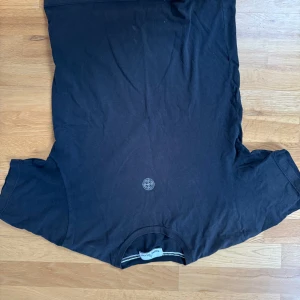 Svart t-shirt från Stone Island - Säljer en svart t-shirt från Stone Island med deras ikoniska logga på bröstet. T-shirten är kortärmad och har en klassisk passform. Perfekt för en stilren look. Storlek S, bra skick.