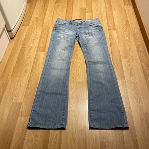 Lågmidjade bootcut jeans - (13) De perfekta ljusblåa lågmidjade bootcut jeansen med otroliga detaljer som kristall knapp och brodering på fickorna. Midjemått rakt över: 38cm, innerbenslängd: 82cm💓