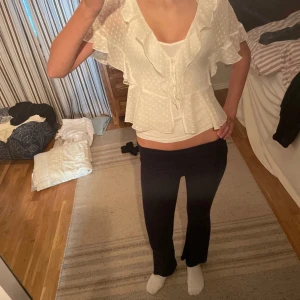 Vit blus med volanger - Säljer en söt vit blus med prickigt mönster och volanger. Blusen har korta ärmar och en v-ringad design. Perfekt för en somrig look! Blusen är ifrån Zara och finns ej att köpa längre. Enda defekten på tröjan är att en av knapparna är sönder men det påverkar ej varan och syns ej 💗