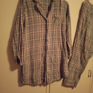 Set Pyjamas skjorta och byxor stl L - Fint set pyjamas skjorta och byxor med fickor och snörning i midjan stl L och i färgen Turkos Rosa. 100% Bomull. Sparsamt använd o fint skick.