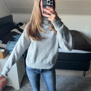 Grå polotröja från Gina Tricot - Säljer en stilren grå polotröja från Gina Tricot. Tröjan har en hög krage och långa ärmar med ribbade muddar. Perfekt för kyligare dagar och lätt att matcha med olika outfits. Skicka ett meddelande vid intresse! 😊Går att vika ner kragen! 