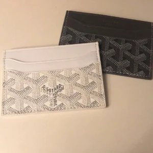 Svart och vit plånbok  - Elegant svart och vit plånbok från  med deras ikoniska mönster. Plånboken har flera fack för kort och en stilren design. Perfekt för den som vill ha något både praktiskt och snyggt.