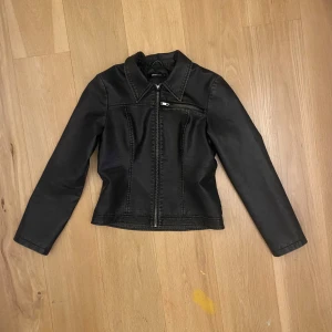 brun skinnjacka från Gina Tricot - Snygg brun skinnjacka från Gina Tricot i storlek S. Jackan har en dragkedja framtill och en stilren design med en bröstficka. 
