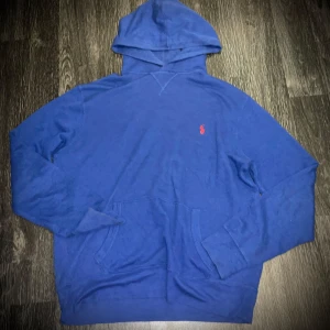 Blå hoodie från Ralph Lauren - Säljer en snygg blå hoodie från Ralph Lauren med det klassiska röda broderade logotypen på bröstet. Tröjan har en känguruficka och långa ärmar, perfekt för en avslappnad stil. Hör av dig vid intresse! 💙