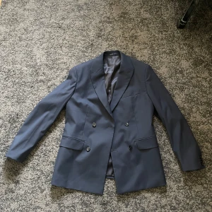 Dubbelknäppt kavaj - Säljer en dubbelknäppt mörkblå kavaj från Mango i storlek 48 slim fit. Nypris är 1499 kr. Kavajen är bara använd en gång och är i perfekt skick. 
