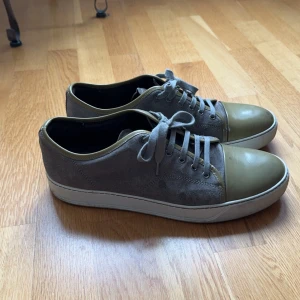 Grå och olivgröna lanvin - Säljer ett par feta lanvin🌟. Skorna har en snygg kombination av mocka och skinn, vilket ger dem en unik look. De är i bra skick med lite slitage på sulan. Perfekta för både vardag och lite mer avslappnade tillfällen. Hör av er för mer frågor!🍁